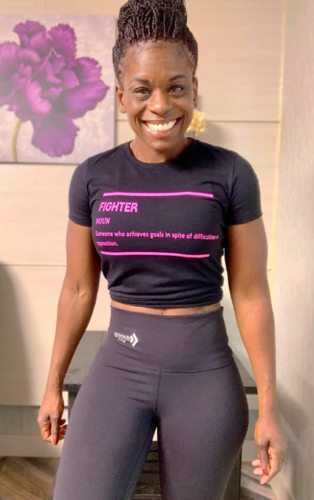 Octavia, smiling at the camera, wearing a shirt that says "Fighter" in pink